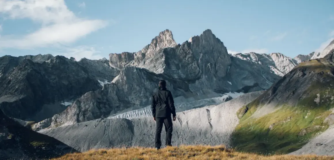 Un randonneur contemple les sommets majestueux du tour des glaciers de la Vanoise 3 jours. Paysage alpin grandiose.