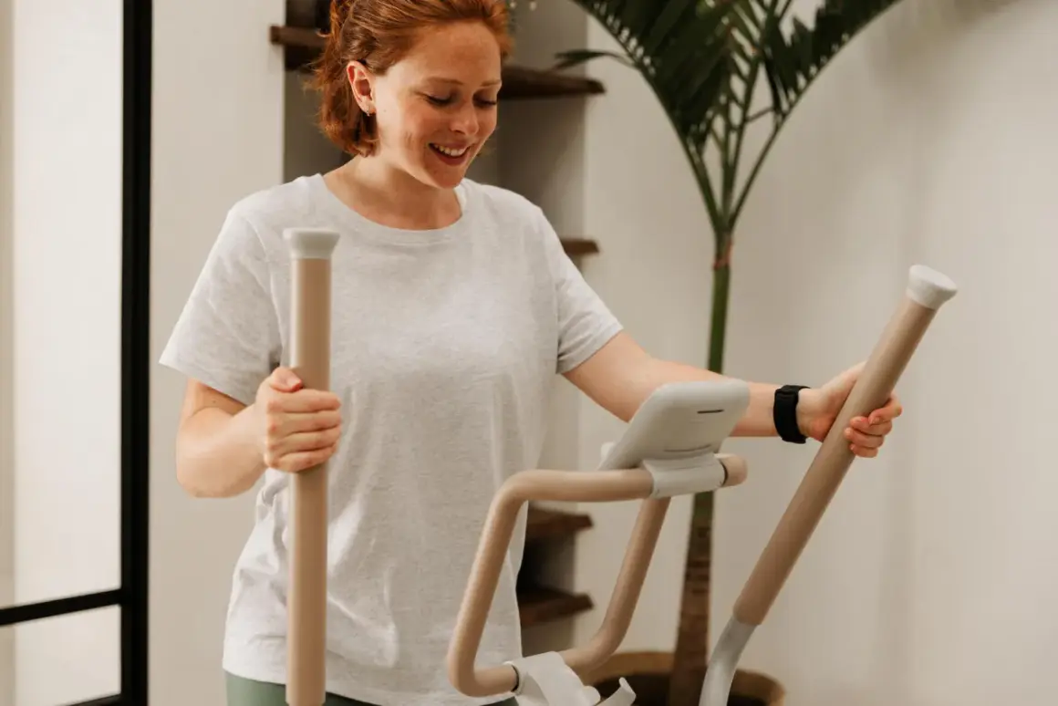 Femme souriante sur un vélo elliptique, suivant un programme vélo elliptique perdre graisse.