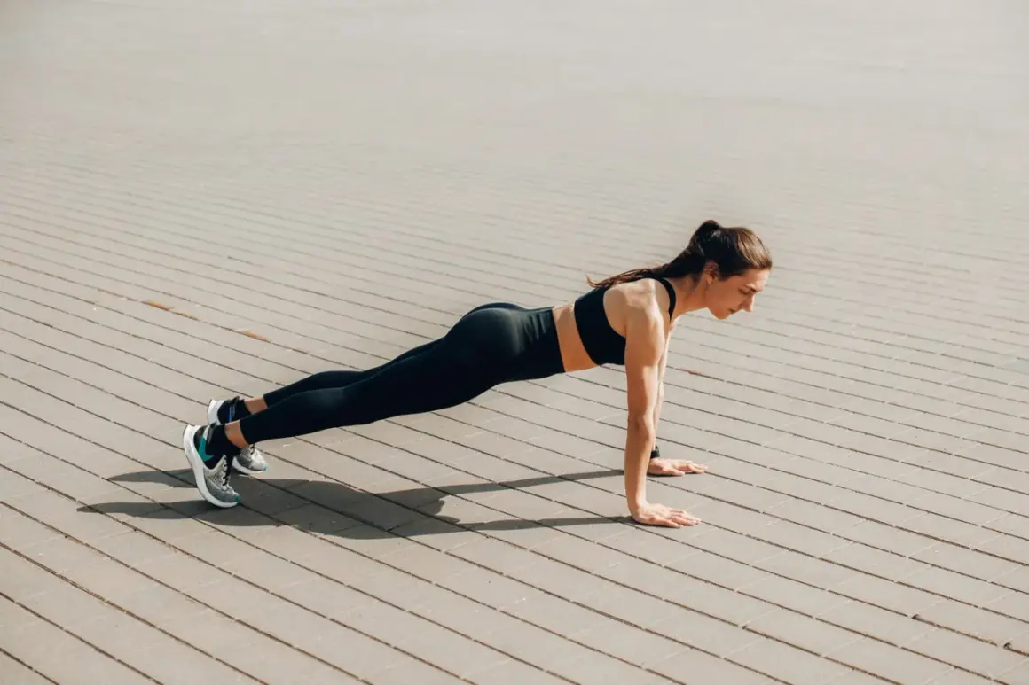 Femme en tenue de sport faisant une planche sur un sol pavé. Elle est concentrée, le corps gainé. Quel est le meilleur sport ? Celui qui vous fait vous sentir ainsi !