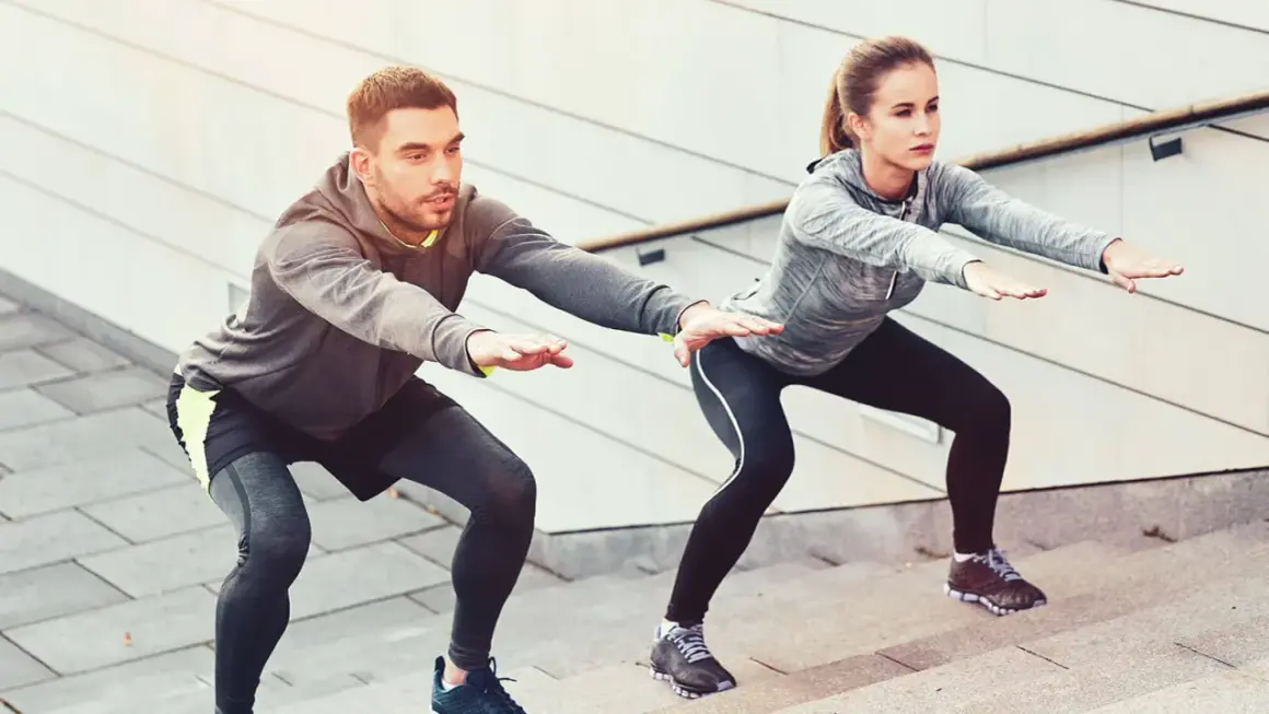Un couple fait des squats sur des marches, un excellent exercice pour perdre du poids.