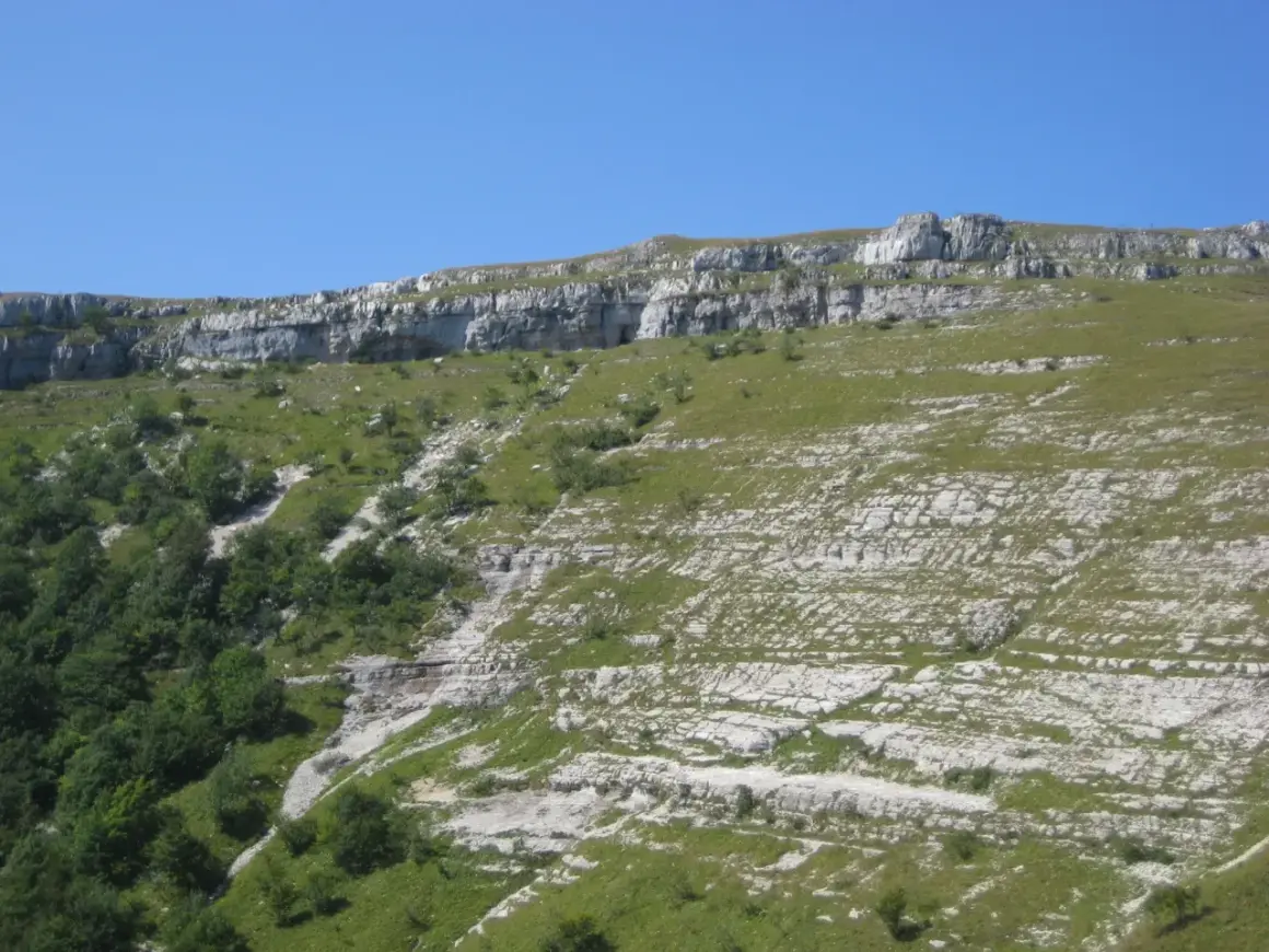 Paysage rocheux et verdoyant du Jura, idéal pour une randonnée boucle 5 jours. Le sentier serpente entre falaises et prairies.
