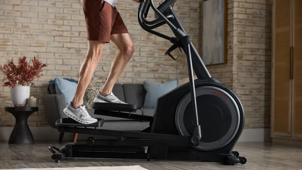 Homme s'entra&icirc;nant sur un v&eacute;lo elliptique, un excellent outil pour la perte de poids et le renforcement musculaire &agrave; domicile.