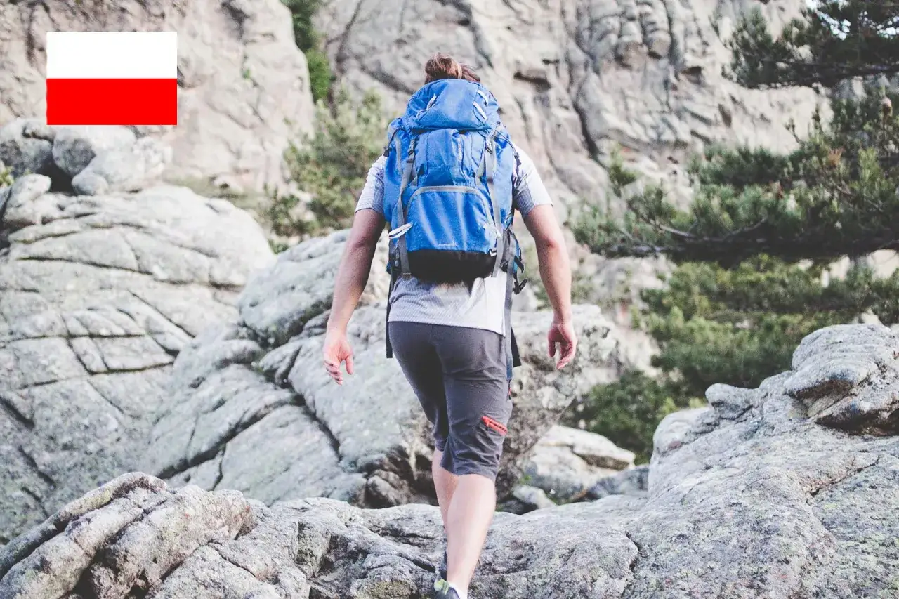 Randonneur polonais avec &eacute;quipement GR20, sac &agrave; dos bleu, traversant un sentier rocheux en Corse.