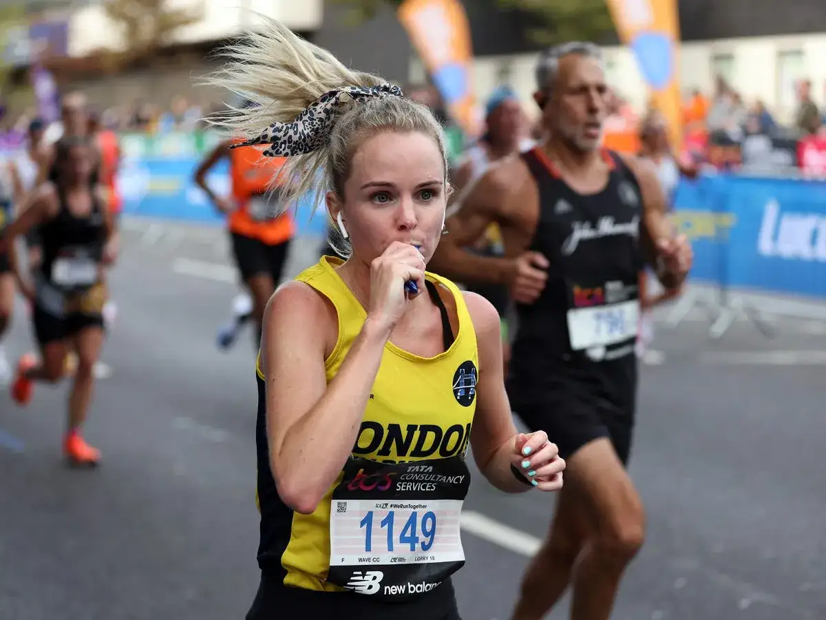 Courseuse en plein effort, elle prend une gorgée d'eau lors de son premier marathon. Son dossard 1149 est bien visible.