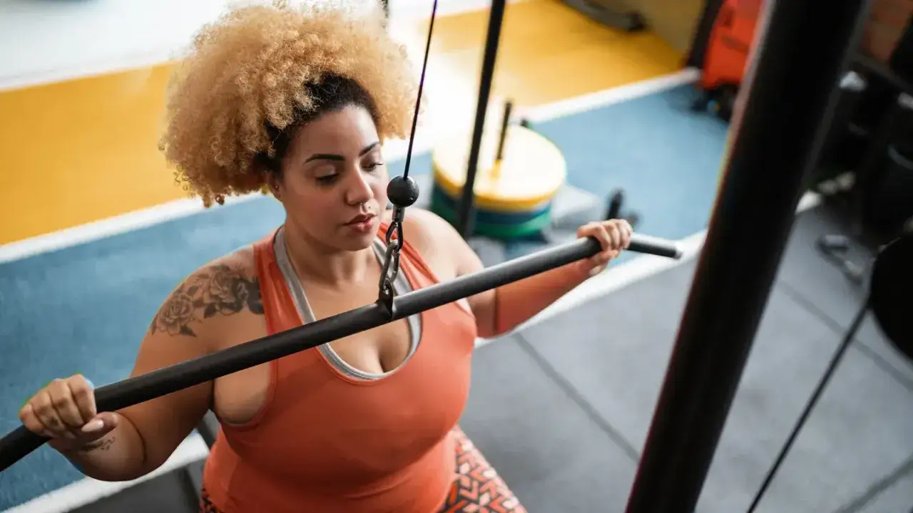 Une femme s'entraîne à la musculation, prouvant que la musculation fait maigrir en renforçant son corps.