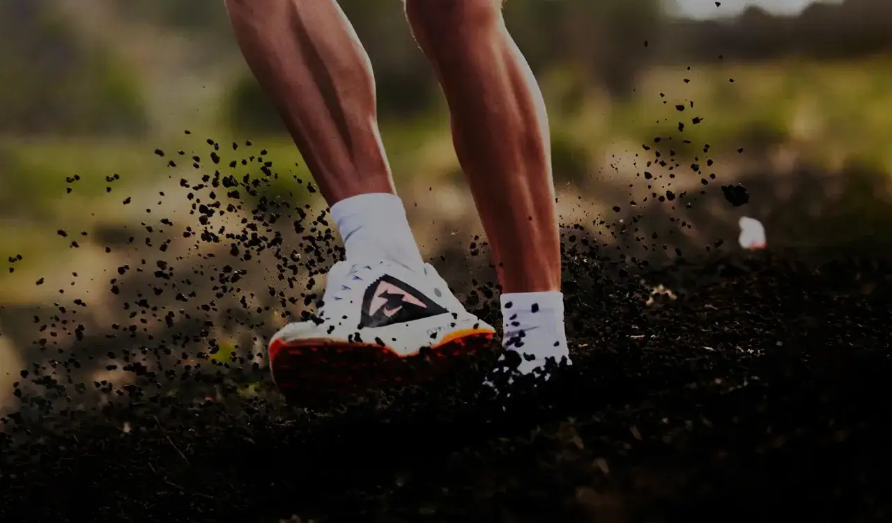 Un coureur en pleine action sur un trail montagne, soulevant la terre à chaque foulée.