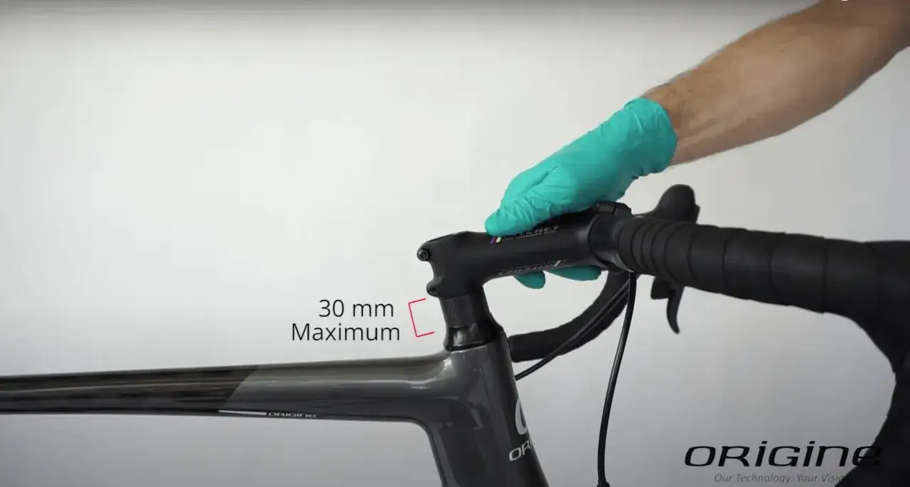Main d'une personne portant un gant vert ajustant le guidon d'un v&eacute;lo de route. Une indication 