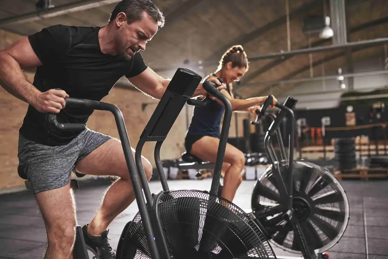 Un homme et une femme s'entraînent intensément sur des vélos d'air, un sport exigeant.