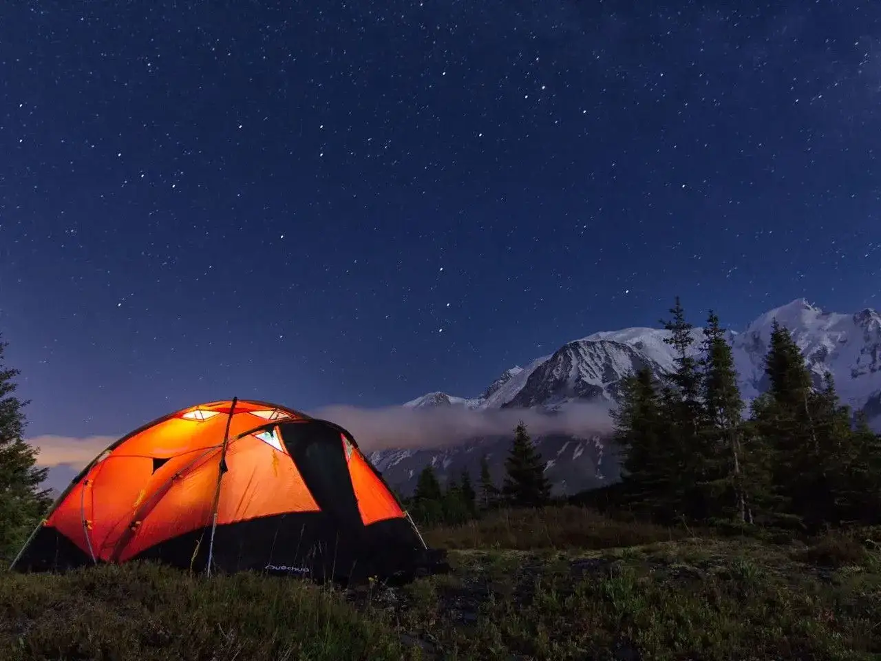 Bivouac sous les &eacute;toiles aux Aiguilles Rouges. Une tente orange illumin&eacute;e dans un paysage de montagne nocturne.