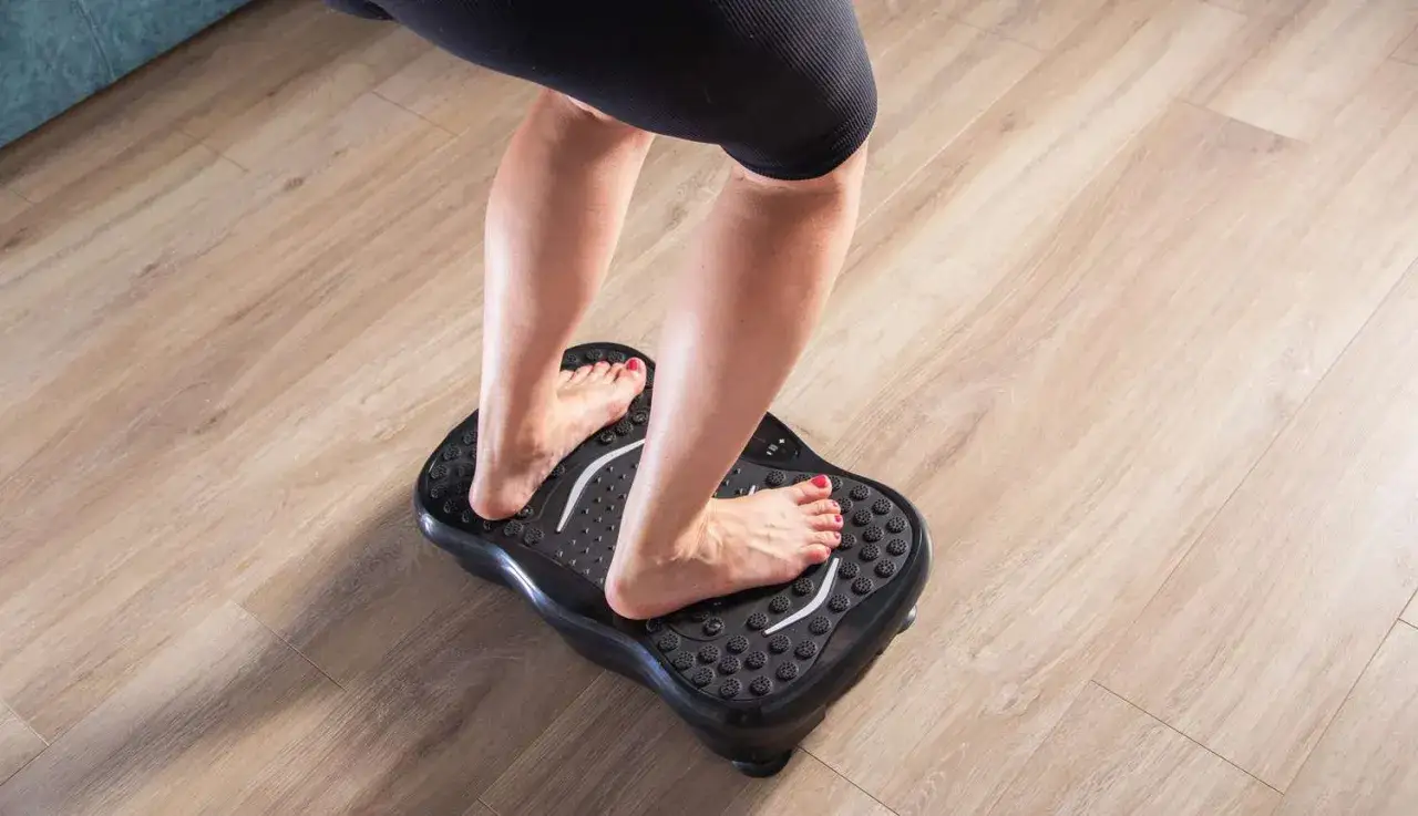 Pieds nus sur une plateforme vibrante, se demandant combien de temps par jour l'utiliser pour un entra&icirc;nement efficace.