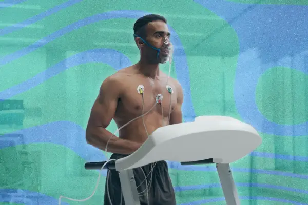 Un homme court sur un tapis roulant, portant un masque à oxygène et des électrodes. Il teste son endurance pour savoir combien de temps pour augmenter sa VO2 max.