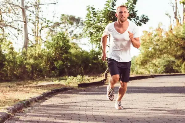 Homme courant sur un chemin pavé, le souffle court, peut-être à cause d'un vo2 max faible.