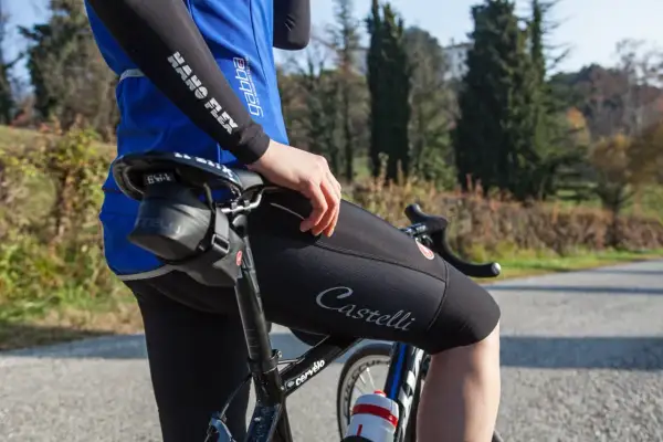 Cycliste ajustant le réglage inclinaison selle vélo route. Vêtement Castelli, maillot bleu, cuissard noir.