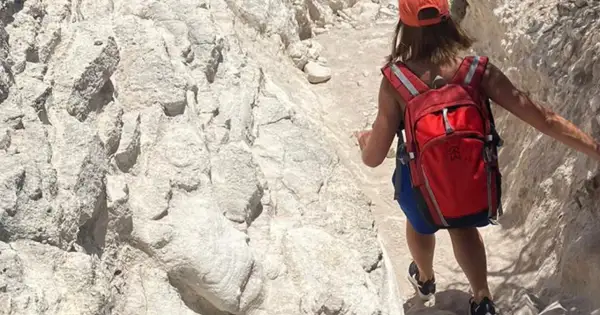 Randonneuse avec sac à dos rouge sur un sentier rocailleux, tout l'équipement nécessaire pour le GR20.