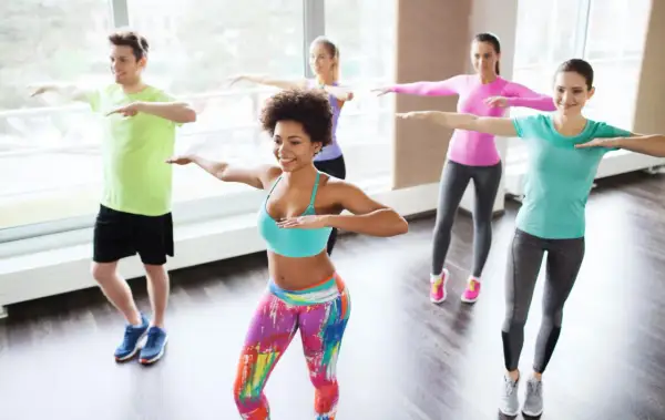 Groupe joyeux en cours de zumba pour maigrir, dansant avec énergie et sourires.