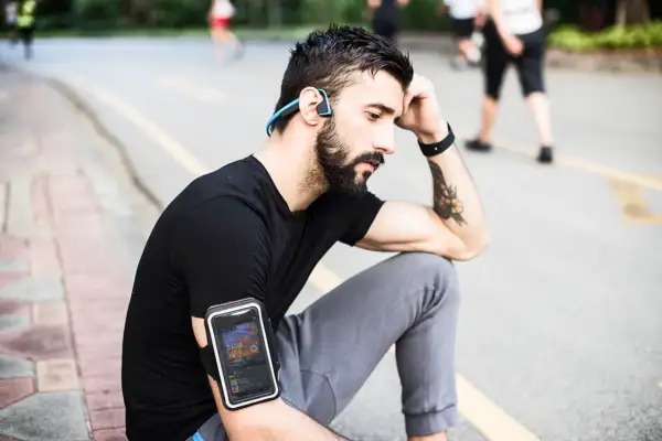 Un homme avec des écouteurs sans fil et un brassard pour téléphone, profitant de courir avec musique sans téléphone.