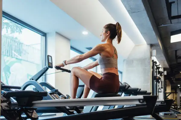 Femme concentrée sur un rameur, profitant du rameur bienfait pour un entraînement complet du corps.