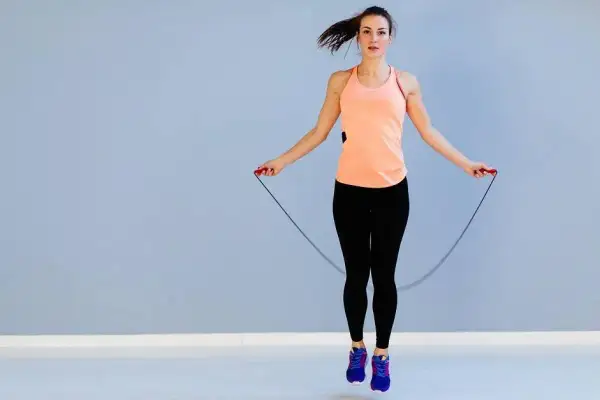 Femme en tenue de sport sautant à la corde, profitant du bienfait corde à sauter pour un entraînement cardio efficace.