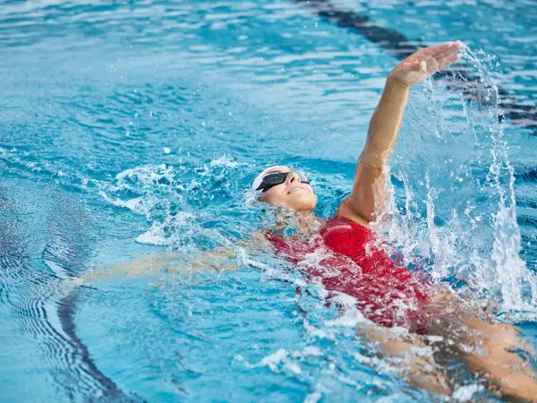 Une nageuse en action, prouvant que la natation est le sport le plus complet. L'eau éclabousse autour d'elle.