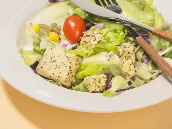 Salade fraîche avec cubes de tofu aux graines, tomate et maïs. Parfait quel petit déjeuner avant sport pour l'énergie.